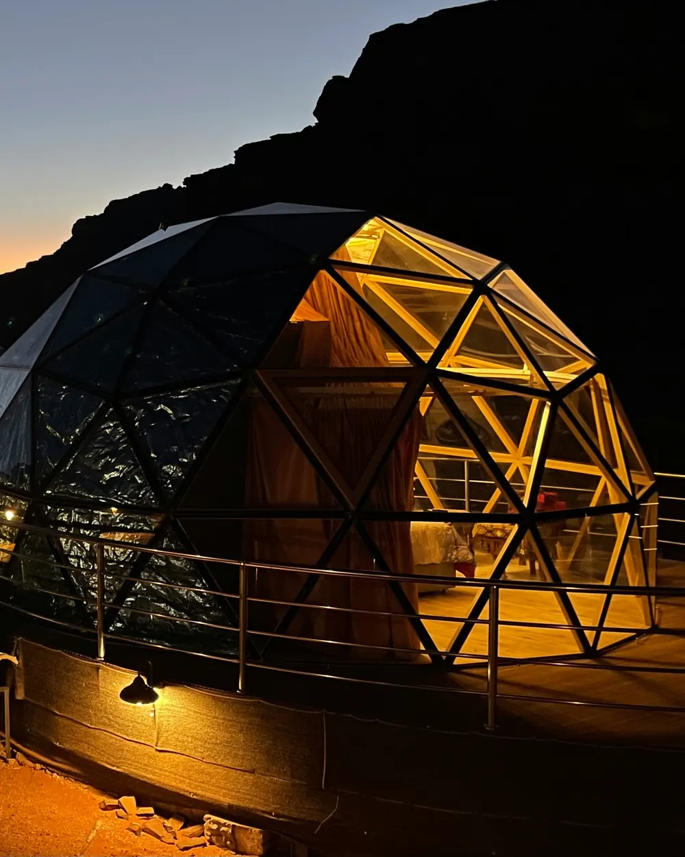 A glass dome glowing at night, with the bed visible inside