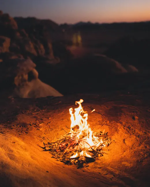 A campfire burning on the sand at dusk